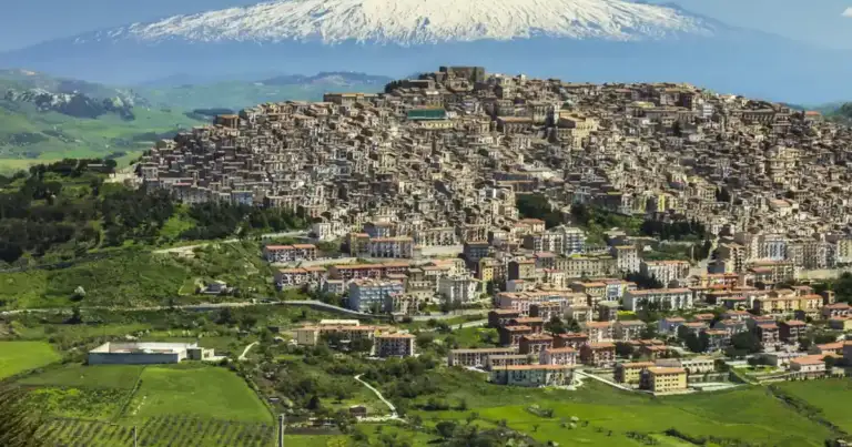 Pueblo en ladera de montaña con volcán nevado de fondo en paisaje rural