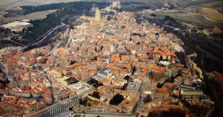 Vista aérea de ciudad medieval compacta rodeada de territorio rural y verde