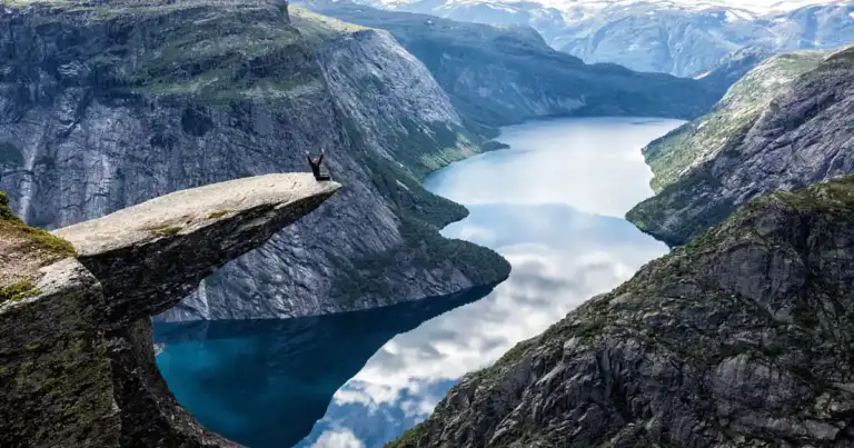 lengua del duende en noruega. se ve una roca que asoma fina y larga sobre el precipicio y abajo piedras y agua