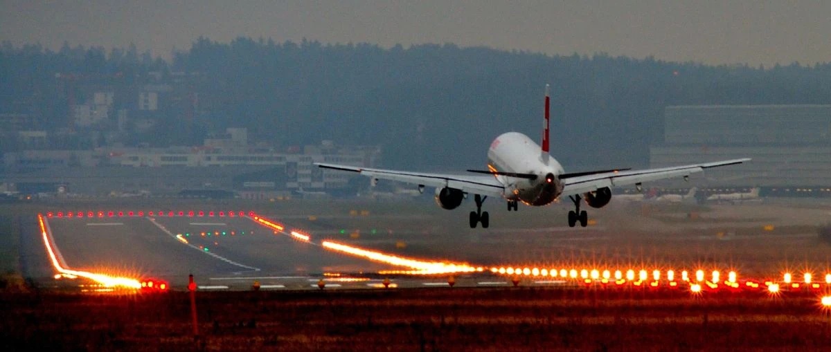 Avión en pista de despegue al atardecer con luces de aterrizaje