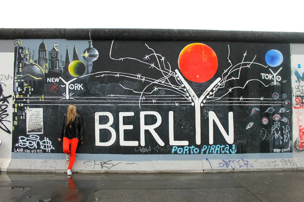 Mural urbano que dice BERLIN con árbol rama y burbujas coloridas, persona vistiendo chaqueta roja