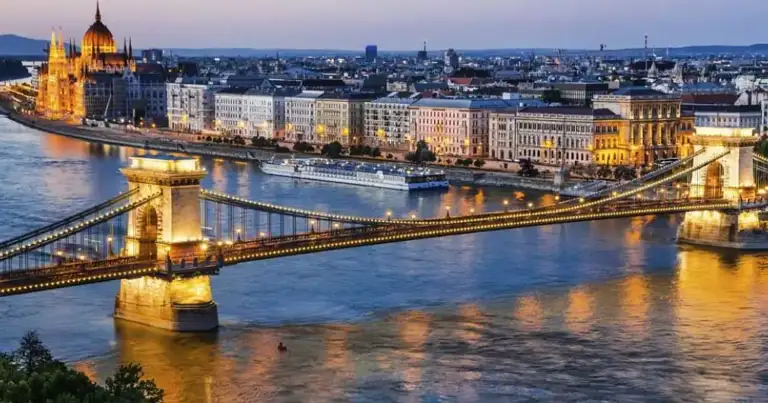 Budapest con río Danubio, iglesia iluminada y puentes al atardecer