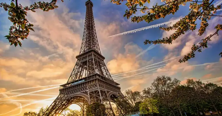 Torre Eiffel al atardecer con cielo dorado y estructuras de hierro