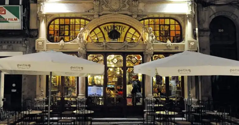 Fachada de café histórico con letrero iluminado y terraza