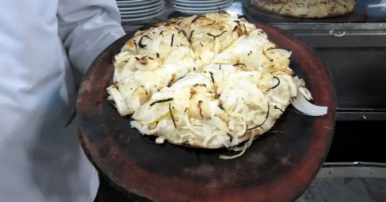 Pizza fugazza argentina con abundante cebolla dorada sobre tabla de madera