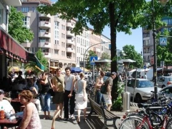 Calle del barrio Schöneberg de Berlín con tiendas, personas, árboles y bicicletas estacionadas