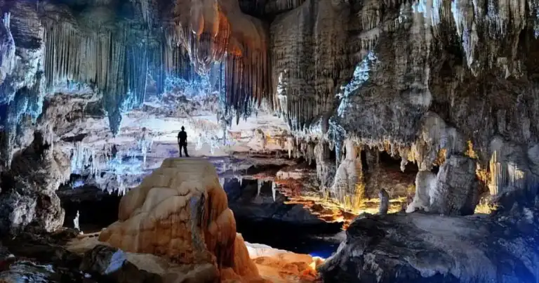 Interior de caverna con estalactitas y estalagmitas iluminadas