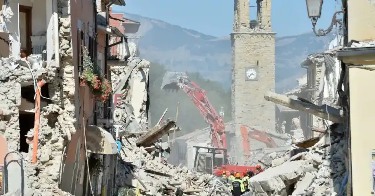 Ruinas de construcciones dañadas con iglesia y grúa de reconstrucción al fondo