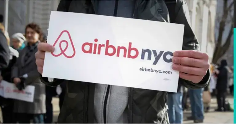 Persona mostrando cartel de Airbnb NYC con logo