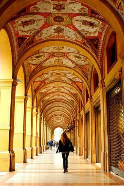 Persona caminando bajo arcadas ornamentales de arquitectura medieval
