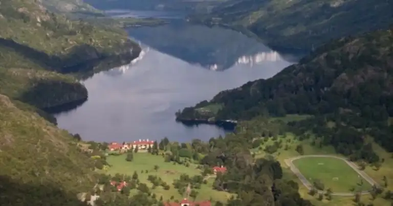 Valle de montaña con laguna espejo y casas dispersas