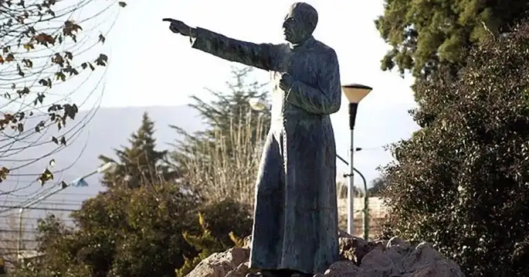 Estatua de cura con vestidura negra frente a montañas