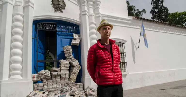 Persona con sombrero en frente de puerta azul con dinero apilado