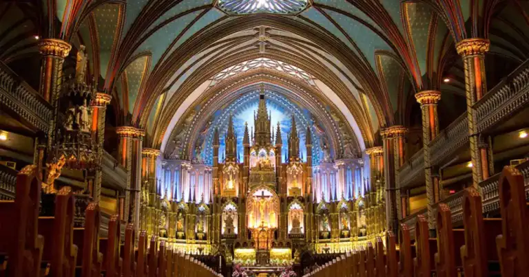 Interior de catedral con bóvedas góticas, columnas doradas y vitrales iluminados
