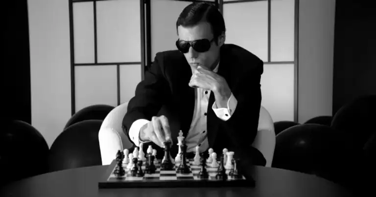 Hombre con gafas oscuras jugando ajedrez en blanco y negro