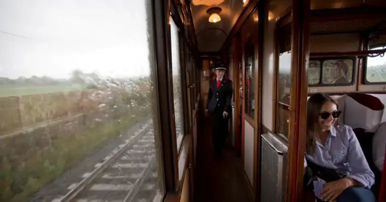 Interior de tren antiguo con pasajeros mirando el paisaje rural