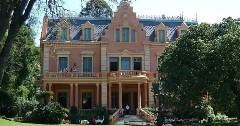 Mansión histórica colonial rosa con porche de columnas y jardinería
