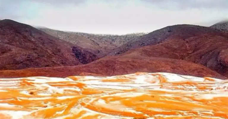 Desierto con nieve cubriendo arena roja en primer plano