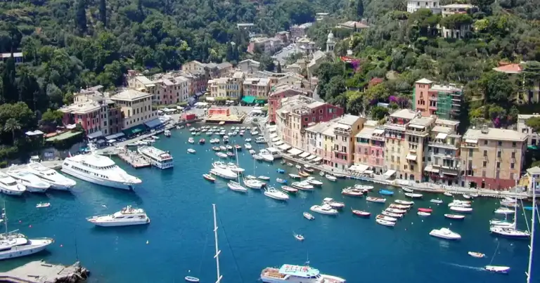 entrada a portofino. se ven yates en el agua azul y la costa colorida de casitas de todos colores