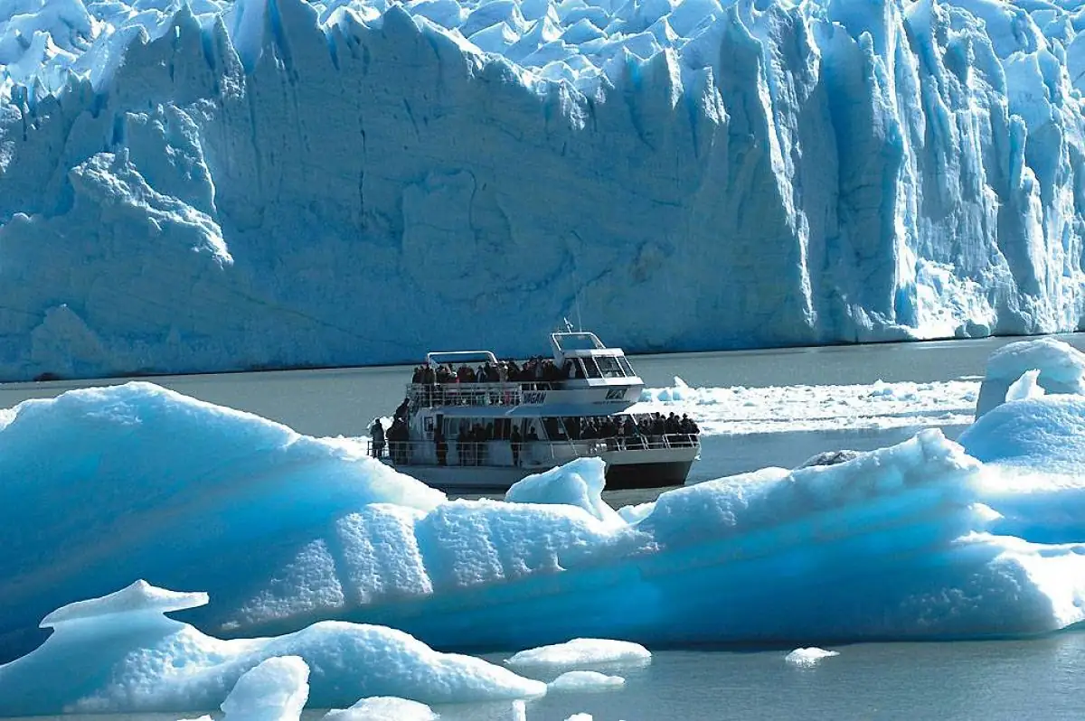 Barco turístico navegando entre témpanos de hielo frente a glaciar