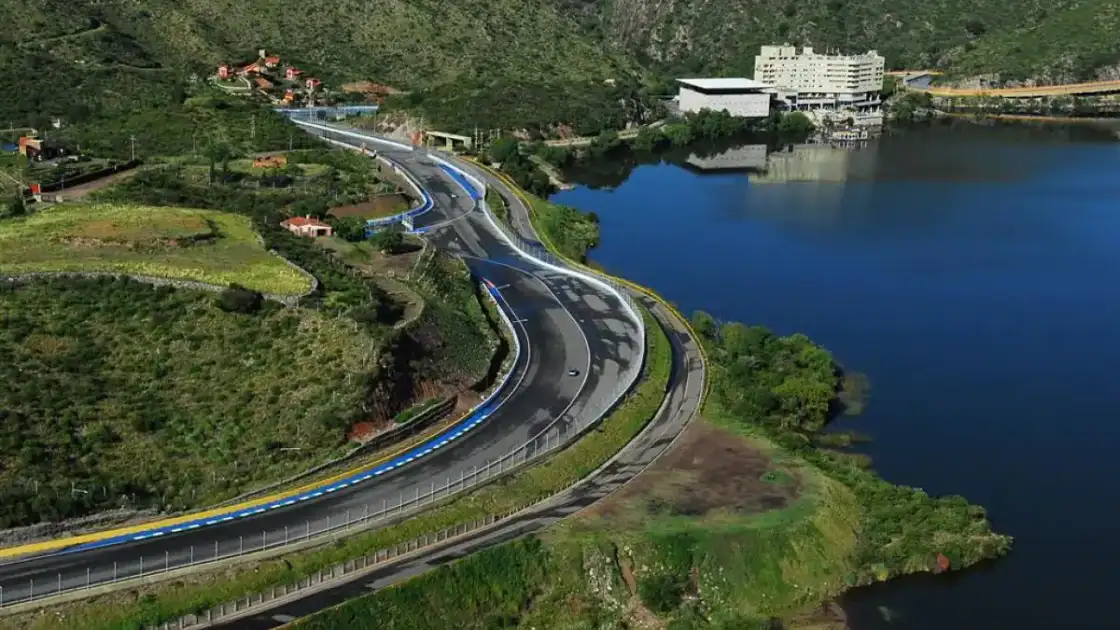 Carretera sinuosa de montaña verde junto a lago azul