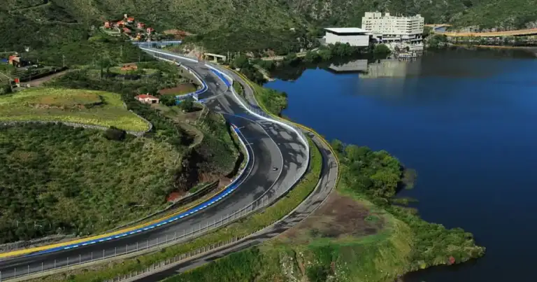 Carretera sinuosa de montaña verde junto a lago azul