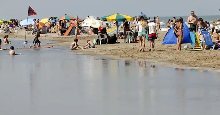 Playa con sombrillas coloridas y personas en agua turbia