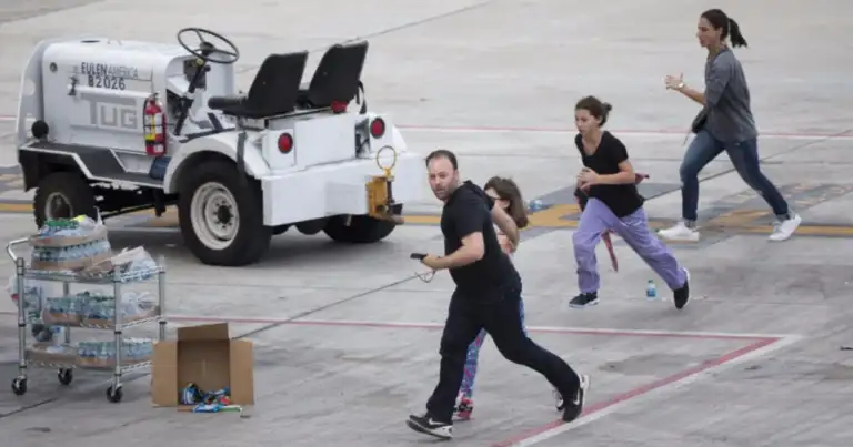 Personas corriendo en aeropuerto desde vehículo de emergencia