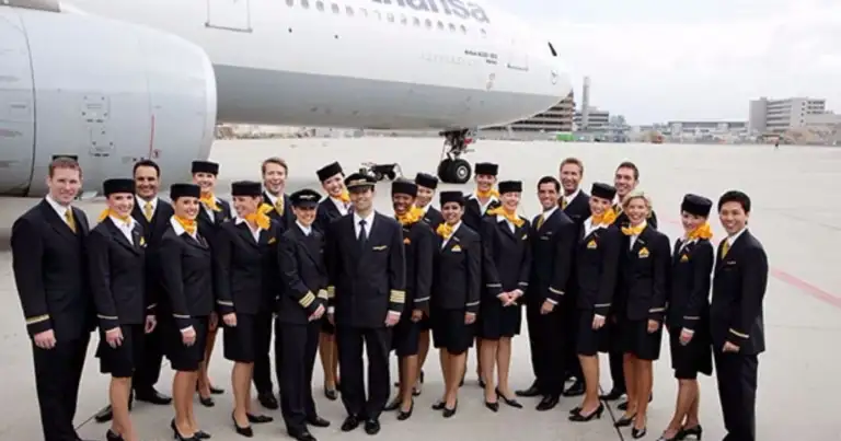 Personal de aerolínea en uniforme frente a un avión Lufthansa