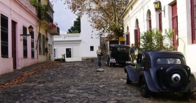 Calle empedrada con casas coloniales de colores y auto antiguo