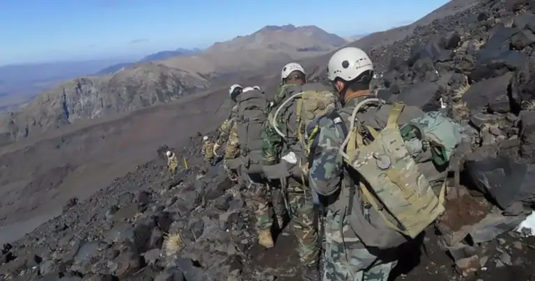 Rescatistas en uniforme en terreno rocoso de volcán con múltiples picos