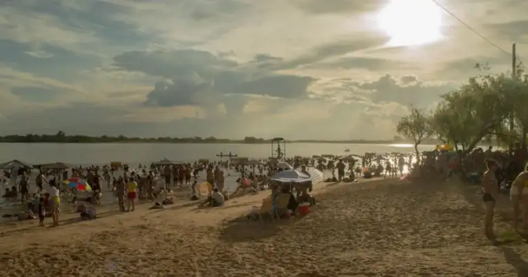 Playa abarrotada de bañistas bajo el sol con estructuras de sombrilla