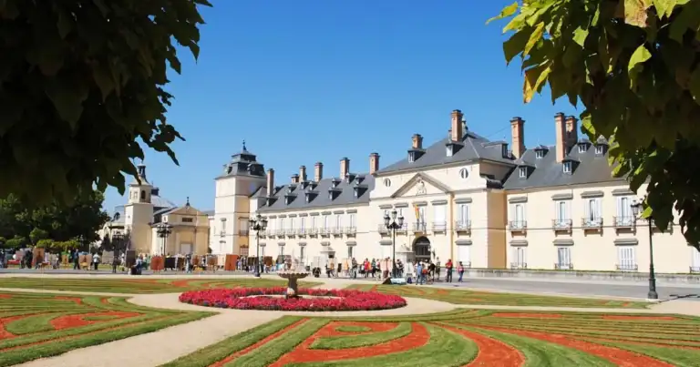 Palacio histórico blanco con jardines formales y camas de flores