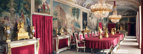 Salón interior del Palacio con frescos en paredes, cortinas rojas y candelabros