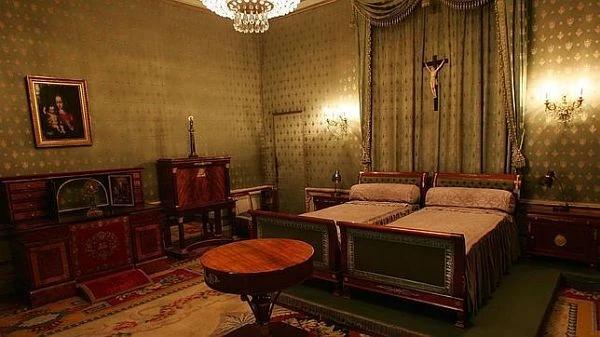 Dormitorio del Palacio con cama de madera, muebles antiguos y chimenea