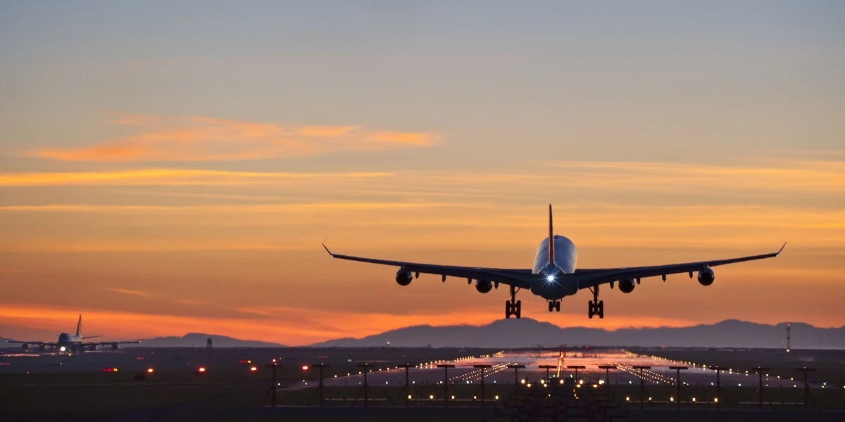 Buscar pasajes baratos tiene trucos que funcionan Avión comercial aterrizando al atardecer sobre pista iluminada
