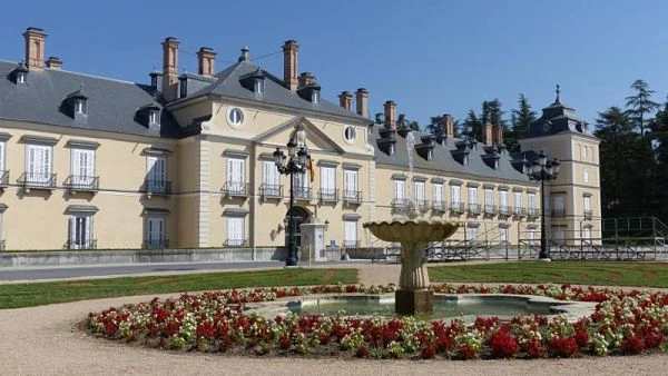 Fachada del Palacio de El Pardo con jardín de flores rojo y árboles