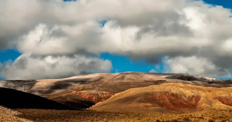 Paisaje de montañas coloridas en los Valles Calchaquíes bajo un cielo con nubes.