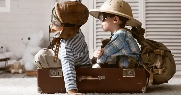 Dos niños con sombreros sentados sobre una maleta vintage