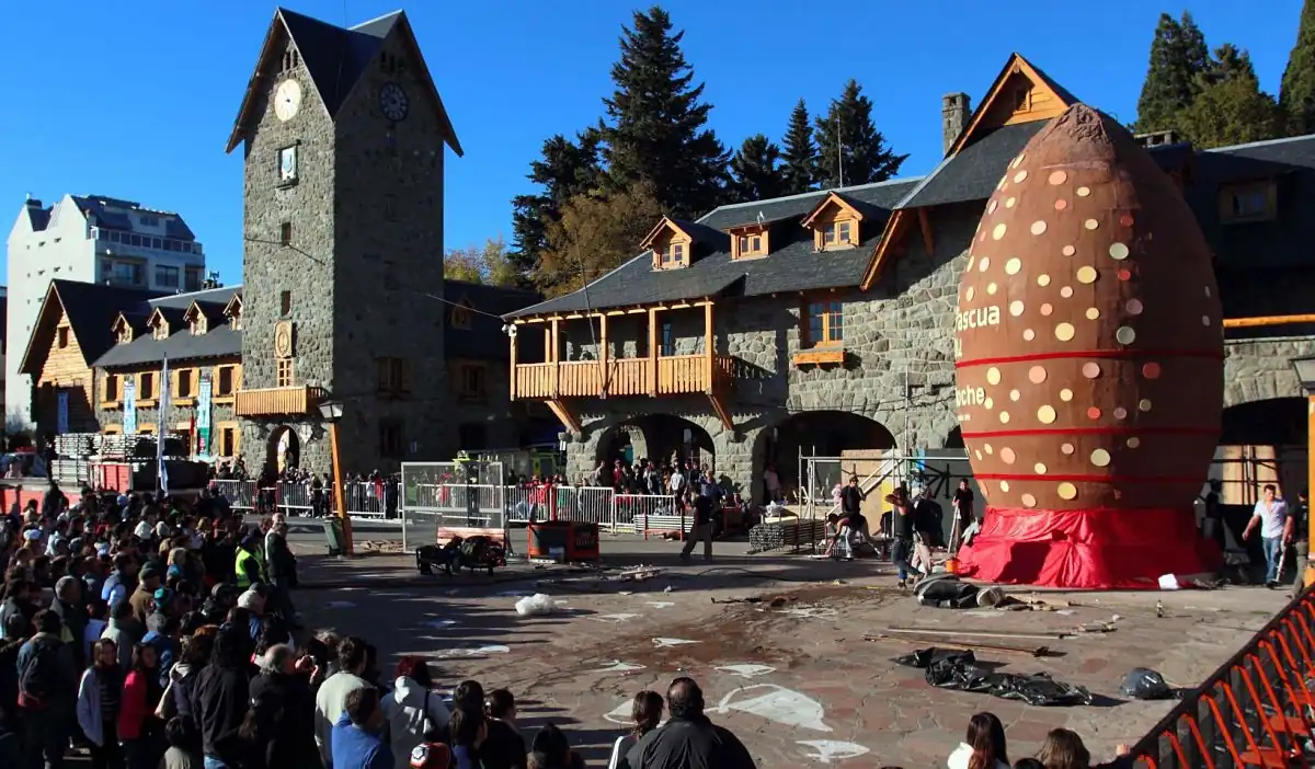 Centro turístico de Bariloche con arquitectura típica, multitud y escultura roja