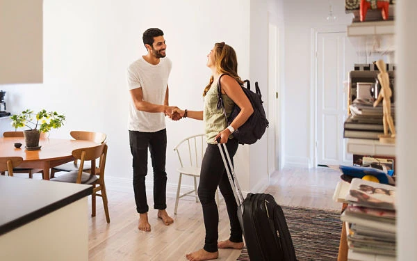 Pareja saludándose en apartamento moderno con maletas