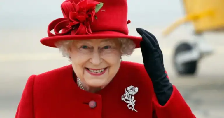 Persona mayor sonriendo, vestida con abrigo rojo, sombrero y guantes negros
