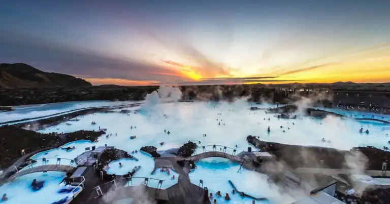 Aguas termales azul turquesa con vapor y roca volcánica al atardecer