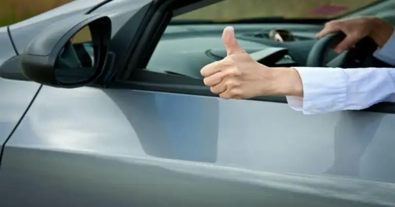 Mano con gesto positivo asomada por ventanilla de automóvil