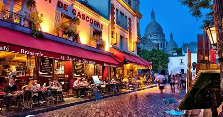 calle de montmartre de noche, iluminada. Toldos rojos y cupula al fondo