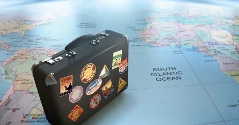 Maleta de viaje negra decorada con pegatinas sobre mapa mundial