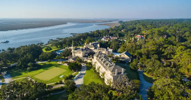 Mansión histórica grande rodeada de jardines y laguna junto a bosque
