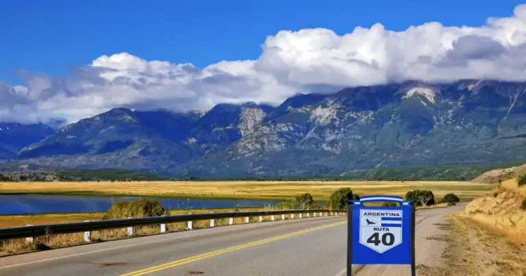 Carretera de dos carriles atravesando paisaje desértico con montañas azules lejanas