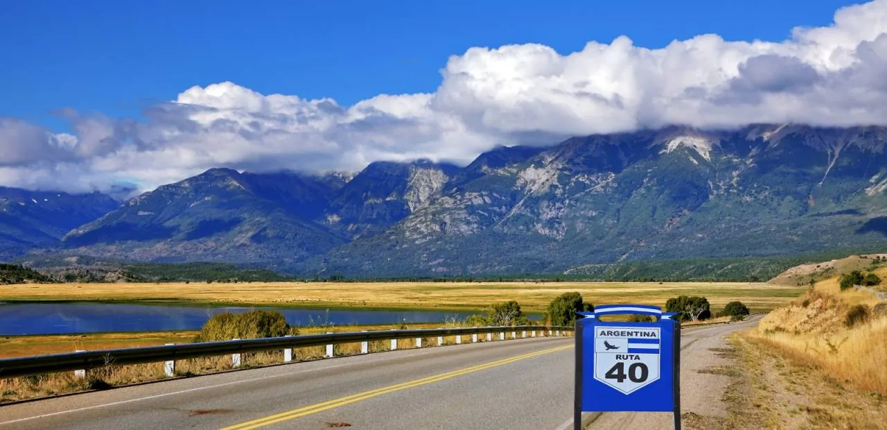Carretera de dos carriles atravesando paisaje desértico con montañas azules lejanas
