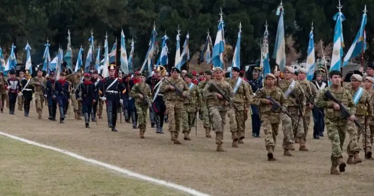 Desfile militar con soldados marchando portando banderas azules